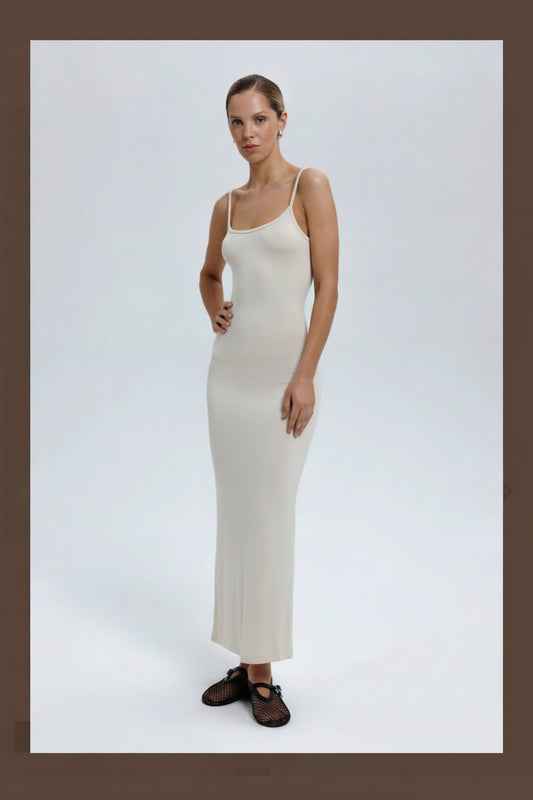 Woman wearing a white slip dress on a plain background